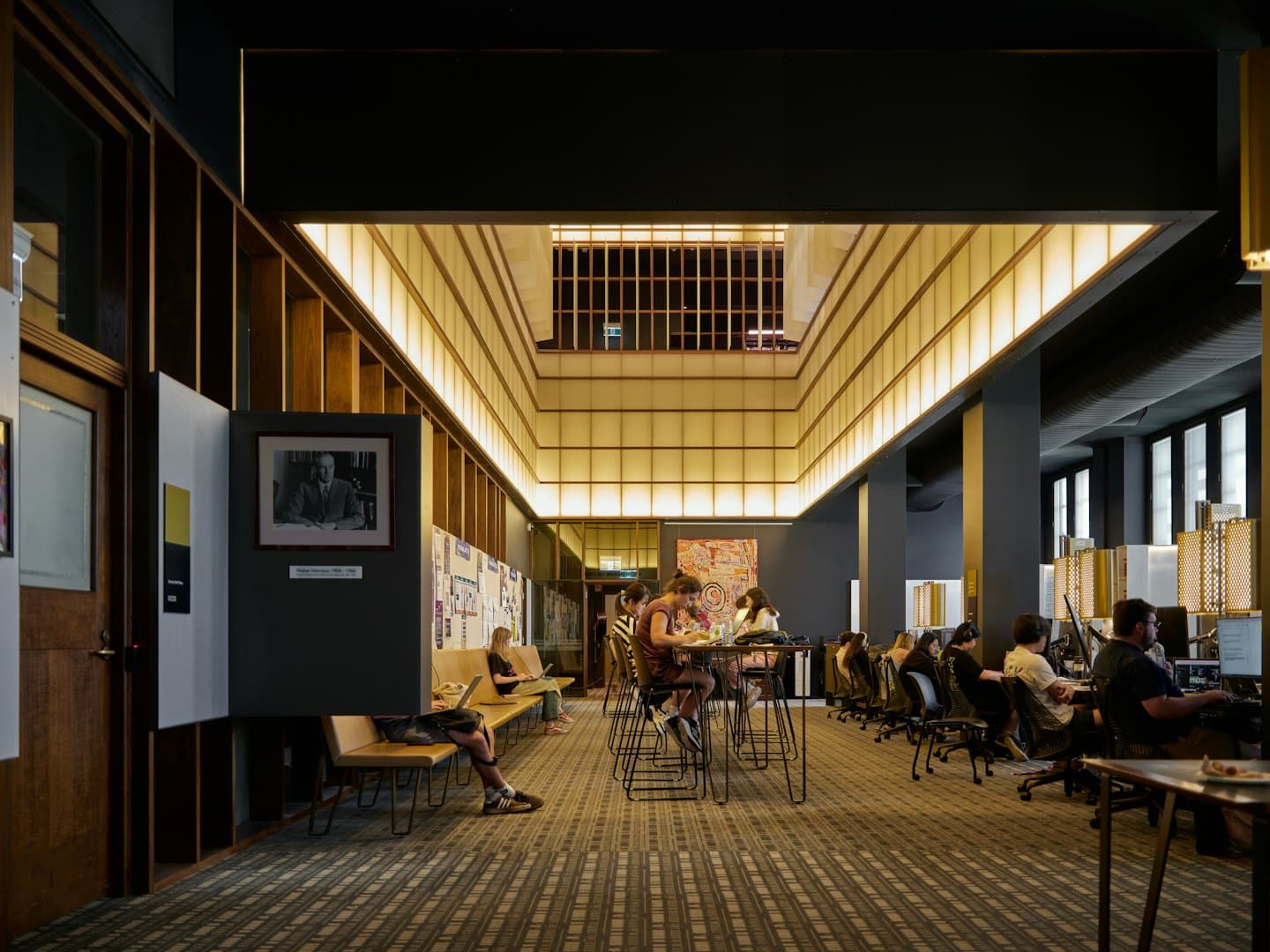 Studenter arbetar på bärbara datorer i ett modernt universitetsbibliotek.